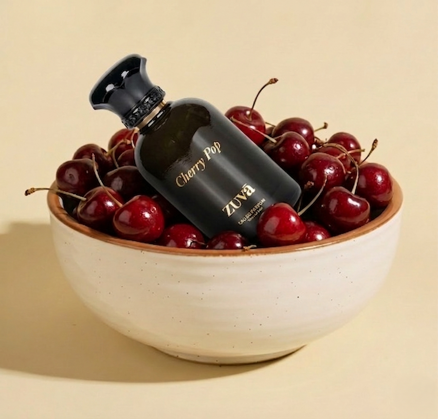 ZUVA Cherry Pop perfume bottle surrounded by cherries in a bowl on a beige background