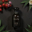 Zuva Cherry Pop perfume bottle with floral and berry decorations on a dark background