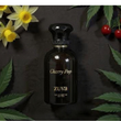 Perfume bottle labeled 'Cherry Pop' by 'Zuva' on a dark background with flowers and leaves.